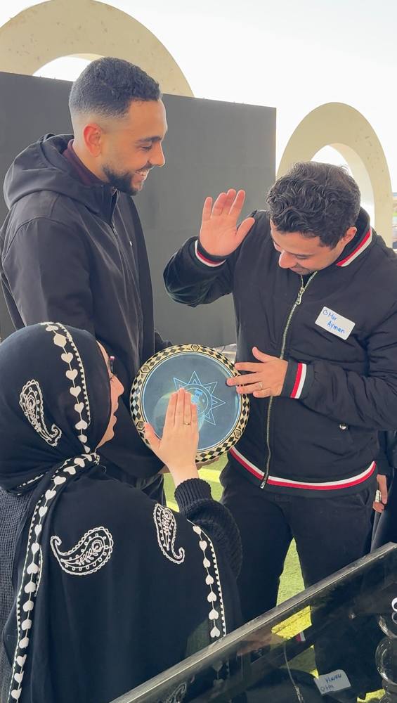 Three team members gathered around a drum, laughing together
