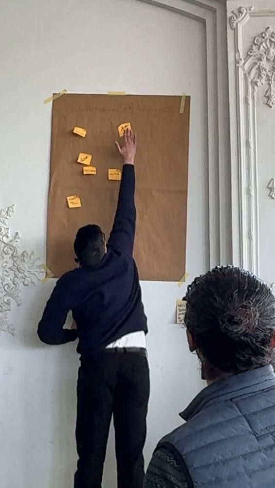 A participant sticking a note on a kraft paper board during a workshop